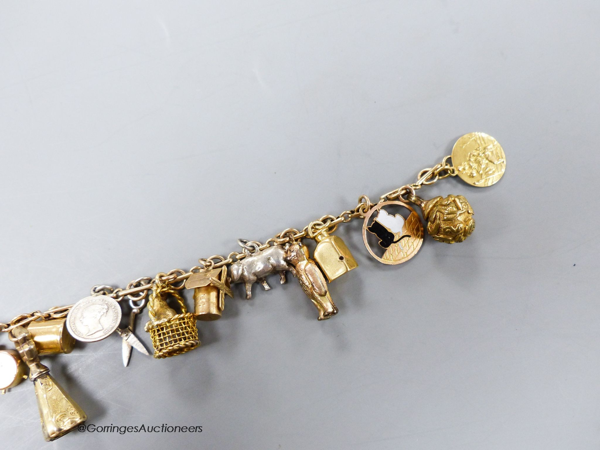 A 9c charm bracelet, hung with nineteen assorted charms, gross 38 grams.